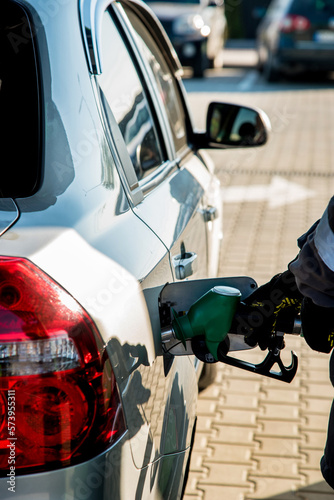 Obraz na płótnie A man refueling a car at a gas station with a hose from an oil column inserted in the tank on a sunny day. w salonie