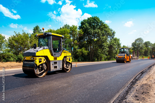 Obraz na płótnie industrial landscape with rollers that rolls a new asphalt in the roadway. Repair, complicated transport movement. w salonie