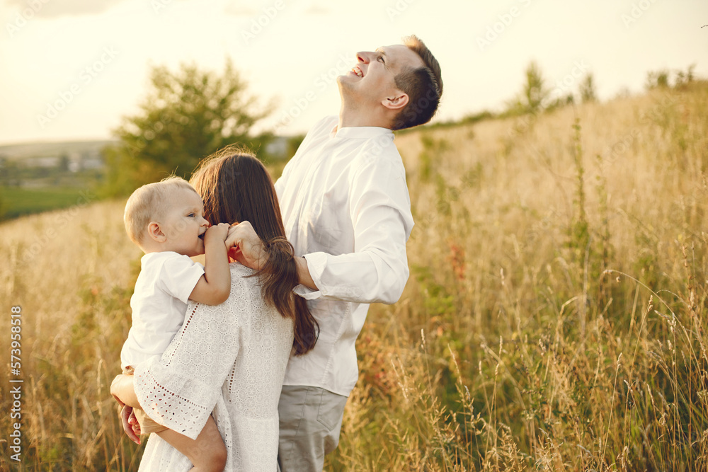 Mother, father and son in white clothes on the field posing for a photo Mother, father and son in white clothes on the field posing for a photo