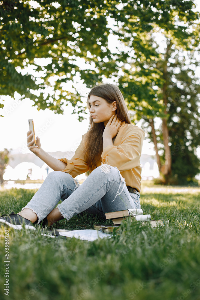Female caucasian student sitting on a grass and using a smartphone Female caucasian student sitting on a grass and using a smartphone