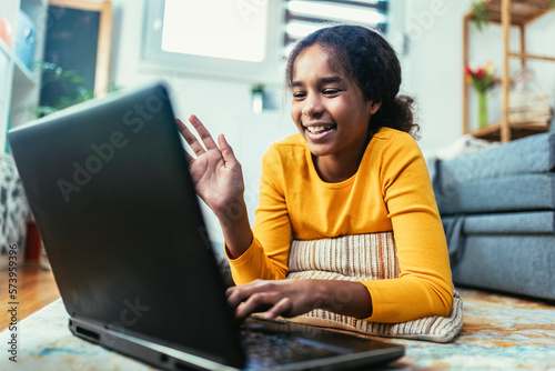 Smiling school African American girl watching the video lesson on computer,happy child have online web class using laptop at home, homeschooling concept