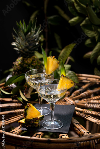 Champagne cocktail with pineapple decoration on a rattan table