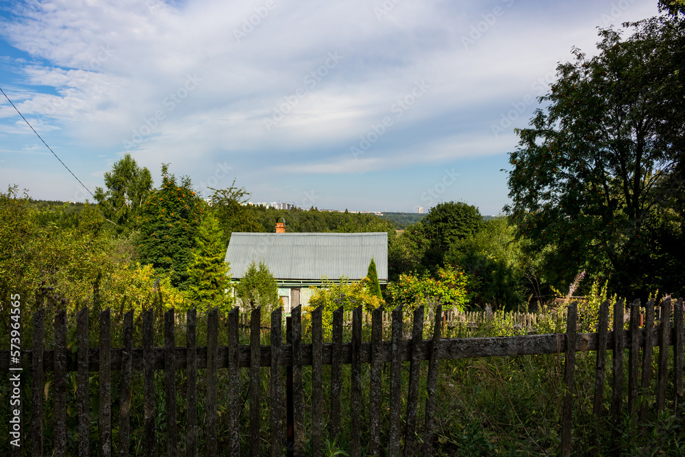 Old fence and grassy rural area with wooden house