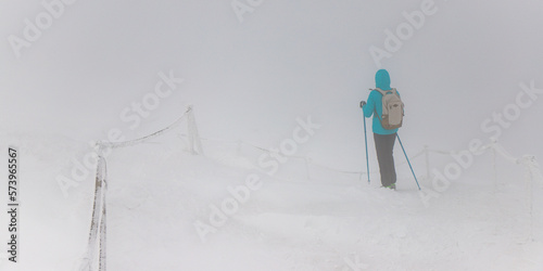 Photography hiker girl walks on snowy mountains in thick fog, low visibility in high mountai