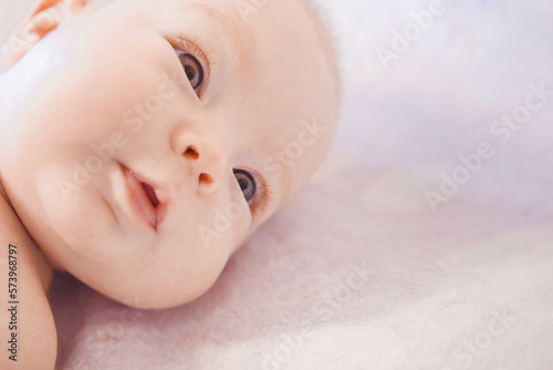 A small baby in a good mood. Baby girl lying on the bed. Beautiful smiling cute kid. Portrait of small cute girl in her cozy white bed. Portrait of adorable smiling newborn child