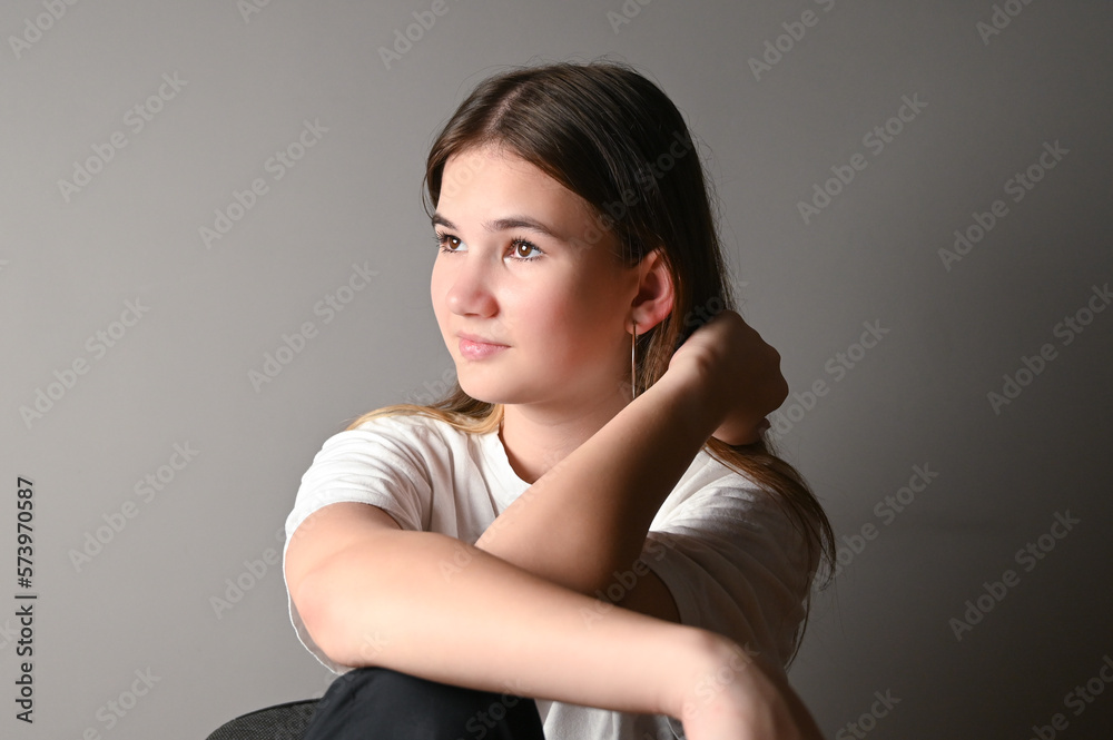 Portrait of a young beautiful thoughtful teen model in white t-shirt on gray background Portrait of a young beautiful thoughtful teen model in white t-shirt on gray background