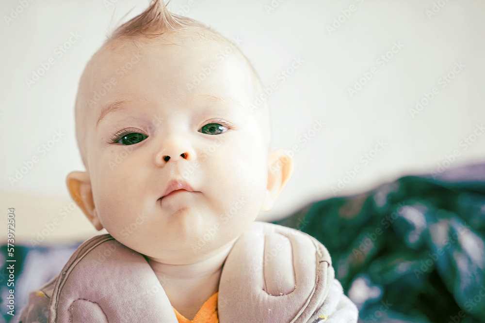 A small baby in a good mood. Baby girl lying on the bed. Beautiful smiling cute kid. Portrait of