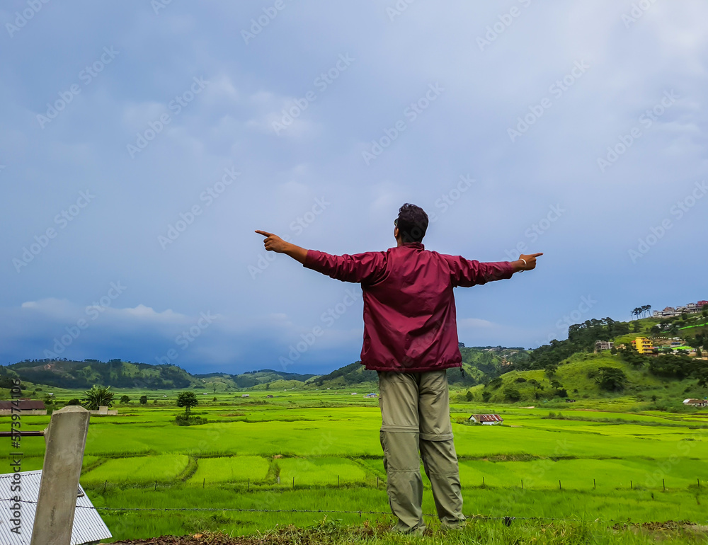 man enjoying natural green paddy field with dramatic sky view at evening from flat angle man enjoying natural green paddy field with dramatic sky view at evening from flat angle