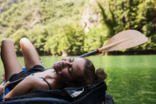 young active girl enjoying a kayak ride on a river in the mountains © Nikola Spasenoski