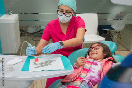 Girl smiling as her dentist prepares to give her teeth a cleaning