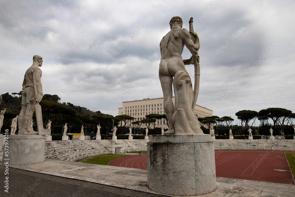 Stadio dei Marmi in Rome, in the foreground marble statues of athletes, in the background the athletics stadium and the Farnesina building.