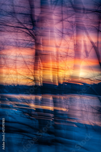 Intentional camera movement photography in winter forest. Abstract color of a sunset in the forest with ICM create a blurred photo like a painting stroke. Bright sunset.