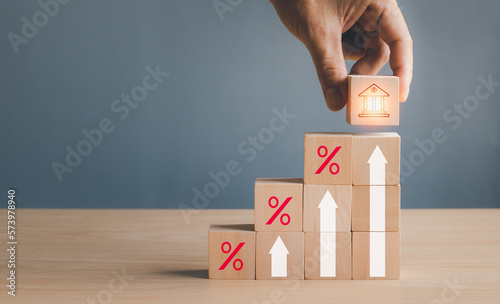concept of financial business, Inflation and economic growth, businessman hand holding wooden block with bank icon above Rows of stacked wooden cubes, arrows showing growth symbols and percentage