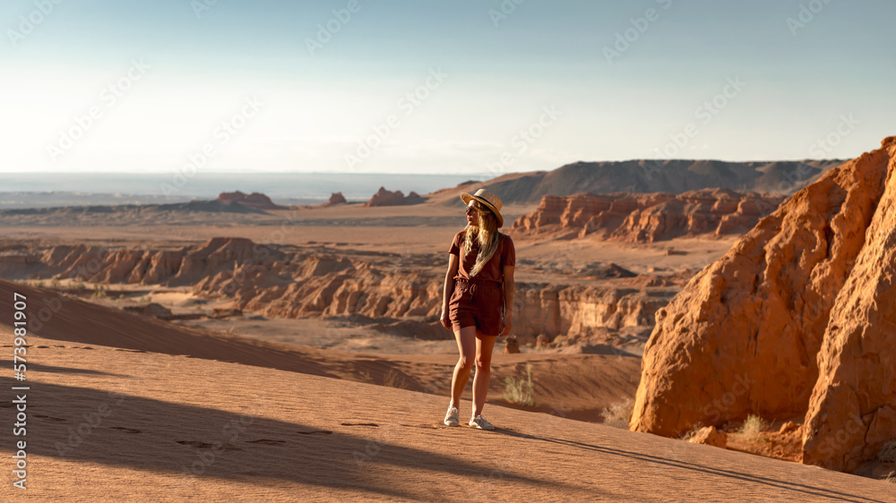 Beautiful girl stands in sunset Gobi desert and enjoys the view Beautiful girl stands in sunset Gobi desert and enjoys the view