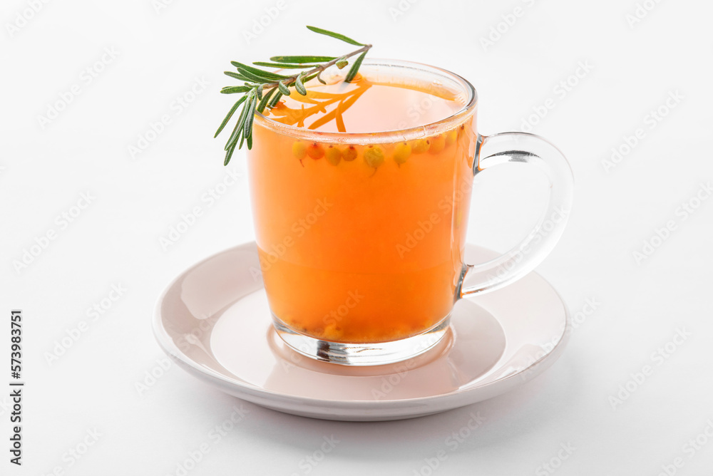 Hot sea buckthorn drink with spices and rosemary in a transparent cup on a white background. Hot sea buckthorn drink with spices and rosemary in a transparent cup on a white background.