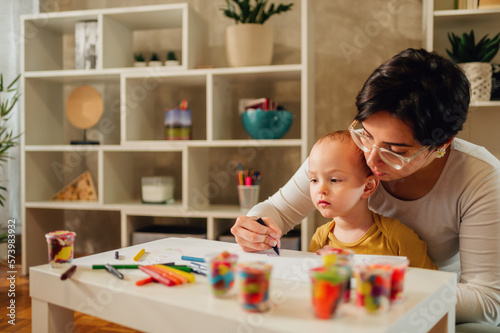 Mother and son drawing with crayons at home and creating art