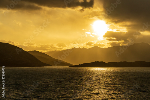 Cruise ship sailing between mountains in Glacier Alley of Beagle channel in Chile at sunrise