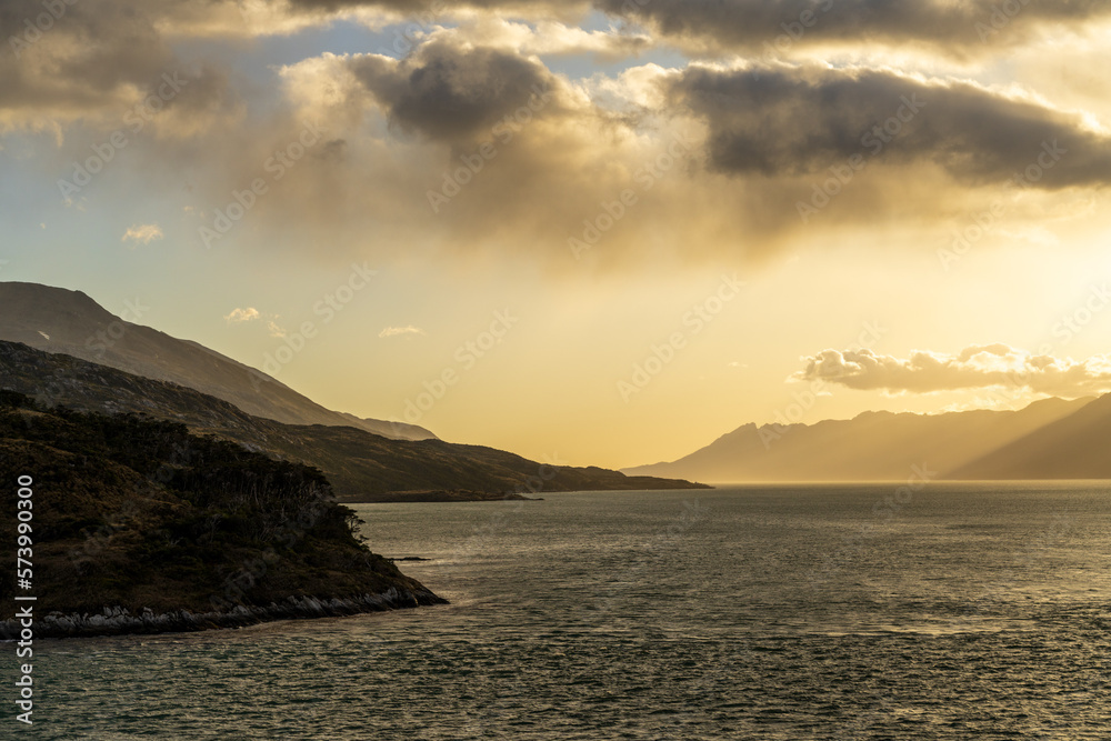 Cruise ship sailing between mountains in Glacier Alley of Beagle channel in Chile at sunrise
