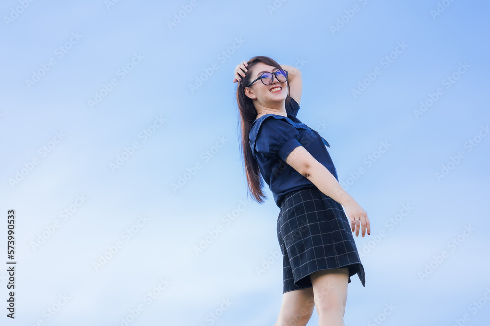 Happy Stretching Relaxation Resting Portrait asian woman Wear dark blue dress stand on bright blue sky background at the city park outdoors. Happy Stretching Relaxation Resting Portrait asian woman Wear dark blue dress stand on bright blue sky background at the city park outdoors.