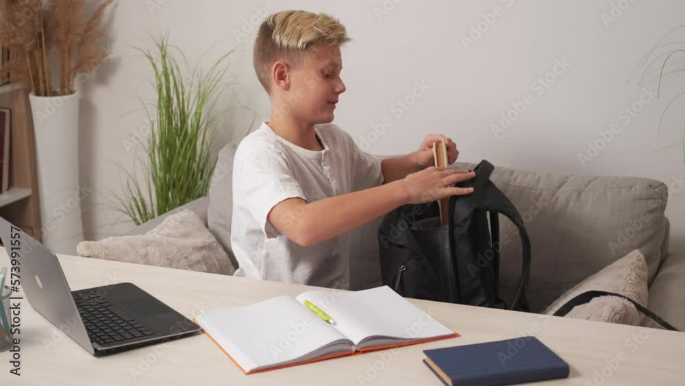 Homework study. Smiling boy. Preparing school. Happy casual teenager kid getting books and work stuff from backpack sitting sofa light room interior. Homework study. Smiling boy. Preparing school. Happy casual teenager kid getting books and work stuff from backpack sitting sofa light room interior.