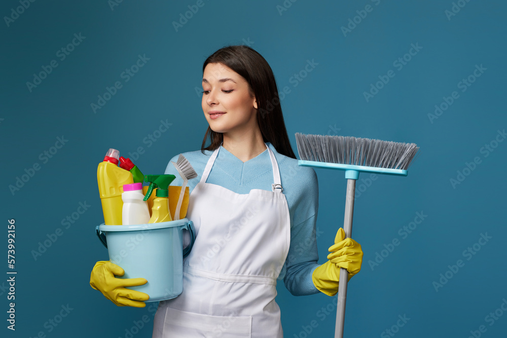 woman in cleaner apron holding bucket of detergents and broom woman in cleaner apron holding bucket of detergents and broom