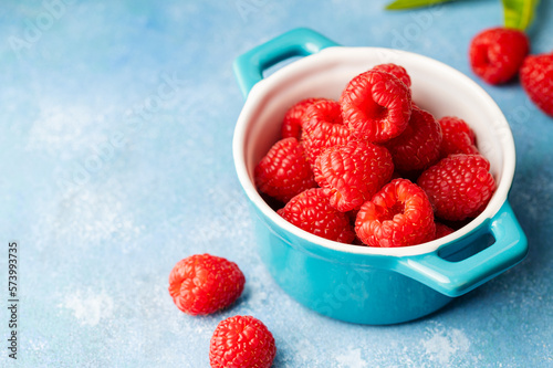 Closeup raspberry fruits in blue bowl  blue background
