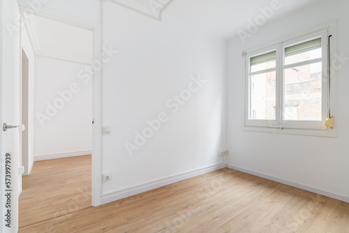 Bright white spacious unfurnished apartment with an window and wooden textured laminate. Concept of modern building or moving to new apartment. Interior design renovation