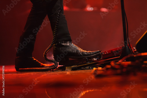 Foto Cool rock singer in stylish leather boots playing on electric guitar
