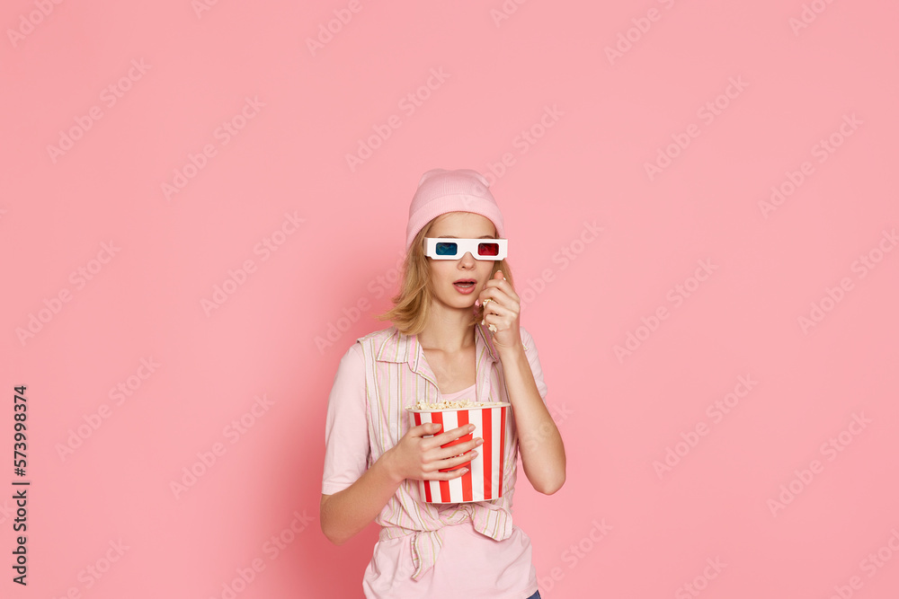 terrified girl watching horror movie , holding bucket of popcorn