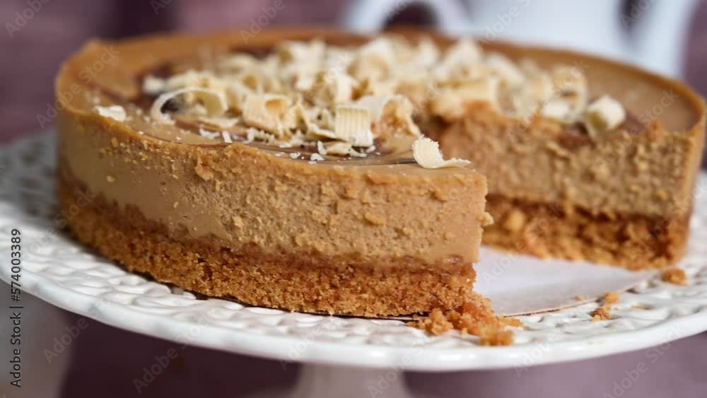 Close up caramel cheesecake on cake stand served with cup of tea. Close up caramel cheesecake on cake stand served with cup of tea.