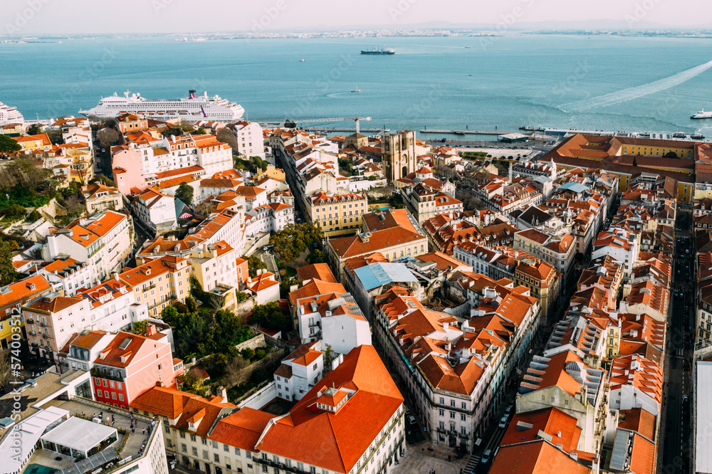 Aerial drone view of Baixa district in Lisbon, Portugal with surrounding major landmarks including Se Cathedral and cruise ship terminal on the Tagus