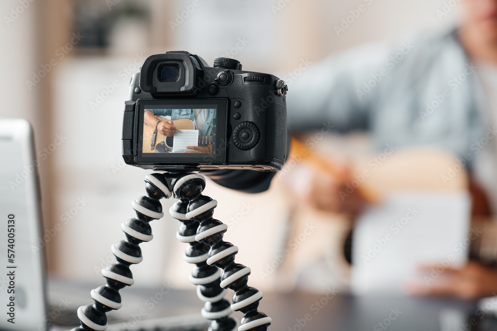 music, blogging and technology concept - close up of camera on tripod recording video or live streaming male guitarist or musician playing acoustic guitar at home