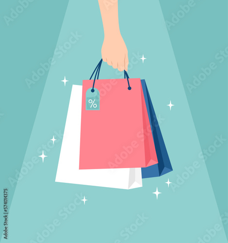 Hand holding glowing shopping bags unger light on a green background. Vector illustration in flat style