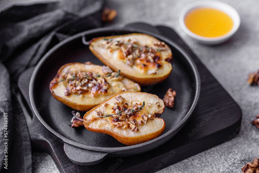 Delicious baked pear with dorblu cheese, walnut and honey on a textured concrete background Delicious baked pear with dorblu cheese, walnut and honey on a textured concrete background