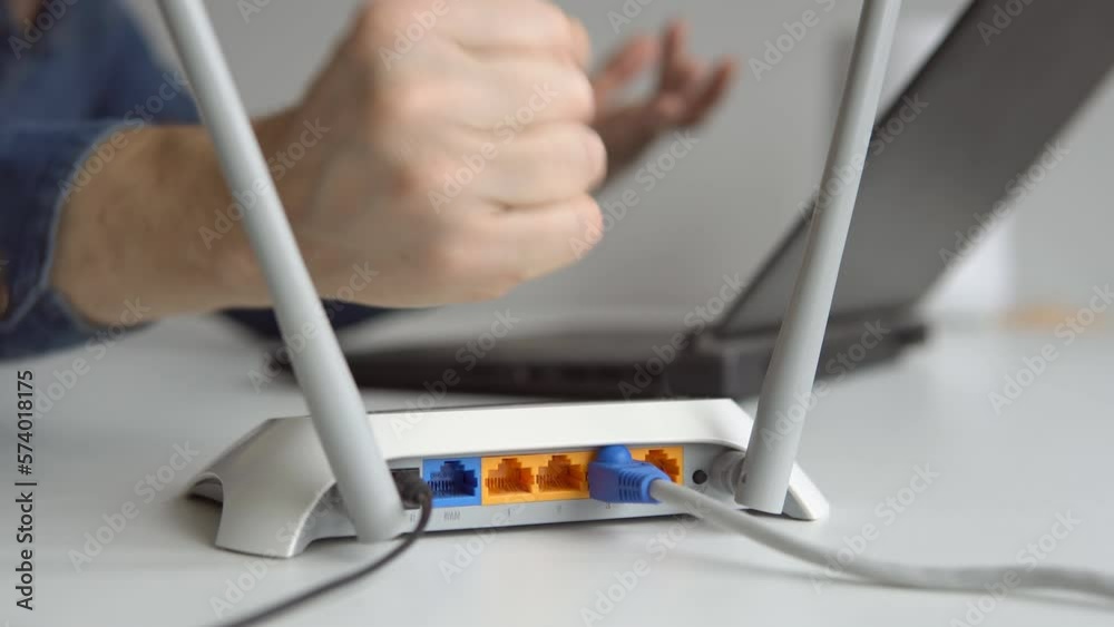Frustrated young man angry at his wifi router modem at work.