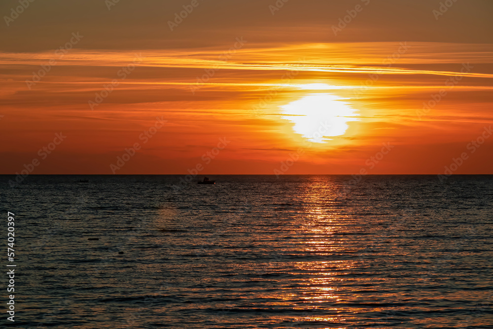 Small fishermen boat with scenic sunset view from Sveti Stefan at Adriatic Mediterranean Sea, Budva Riviera, Montenegro, Europe. Reflection of sun beams on water surface. Summer vacation atmosphere Small fishermen boat with scenic sunset view from Sveti Stefan at Adriatic Mediterranean Sea, Budva Riviera, Montenegro, Europe. Reflection of sun beams on water surface. Summer vacation atmosphere