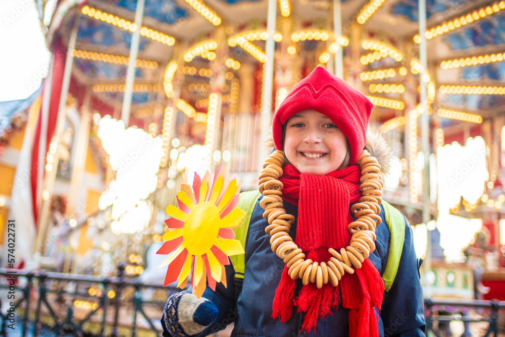 smiling boy with bagel beads, at the traditional Russian festival dedicated to the meeting of spring, the week of pancakes, Shrovetide. the child stands at the decorations for the Maslenitsa holiday