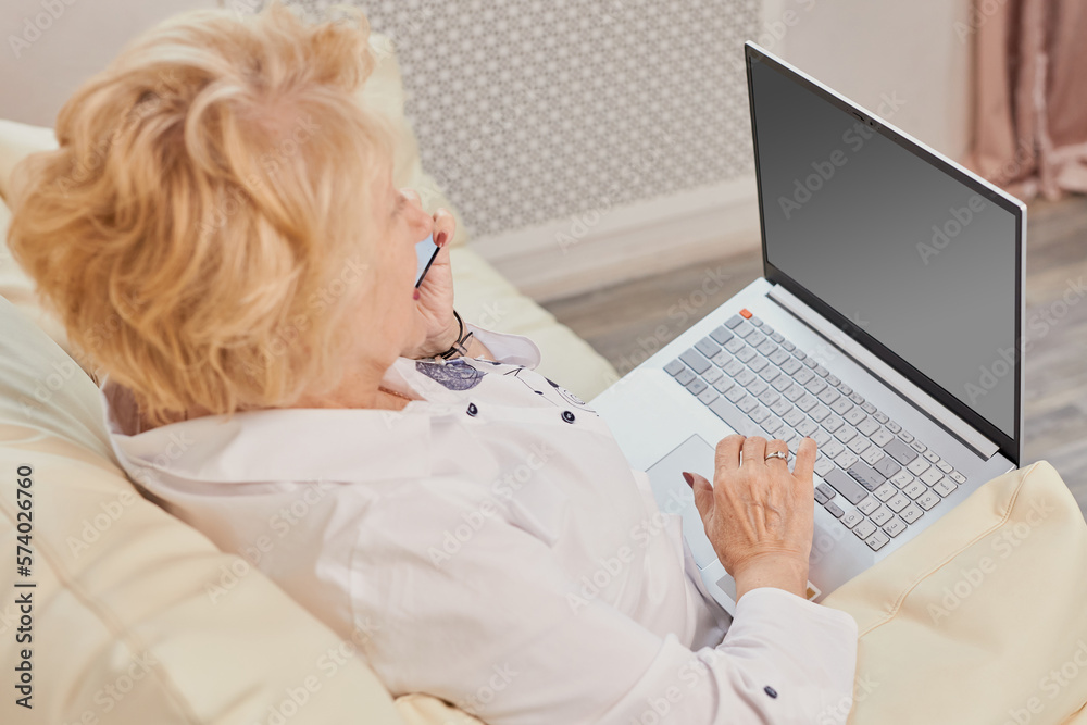 Smiling senior woman having conversation on phone, working on laptop at home, copy space. Beautiful old lady freelancer working from home, talking with clients on smartphone Smiling senior woman having conversation on phone, working on laptop at home, copy space. Beautiful old lady freelancer working from home, talking with clients on smartphone