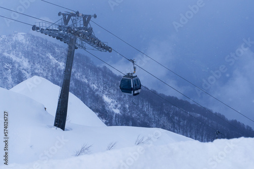 ski lift cable transporting skiers at mountain hills during snowing storm 