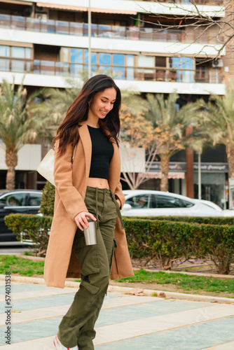Happy young woman with casual clothes walks on the street
