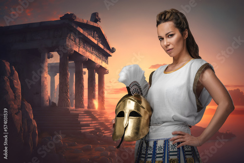 Art of warrior woman dressed in tunic holding plumed helmet around greek building. photo