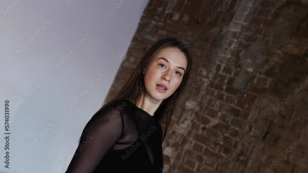 Attractive woman dancing in the studio with brick walls - looking in the camera and moving towards it Attractive woman dancing in the studio with brick walls - looking in the camera and moving towards it