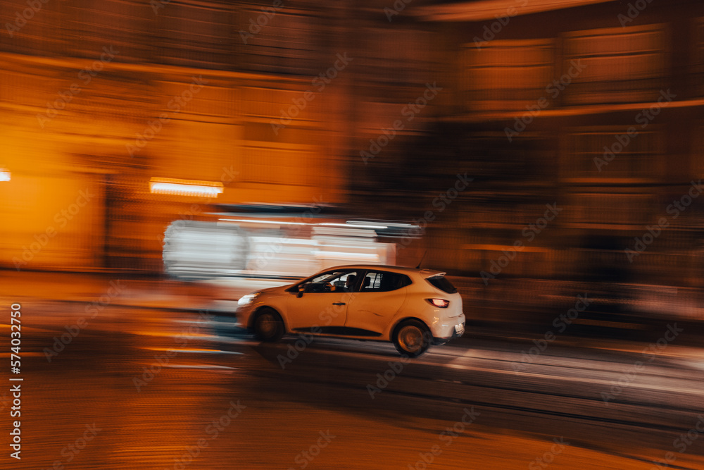 White car in motion at night, panning photo, blurry background, movement