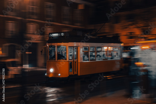 Lisbon tram in motion, panning, driving at night, blurry background