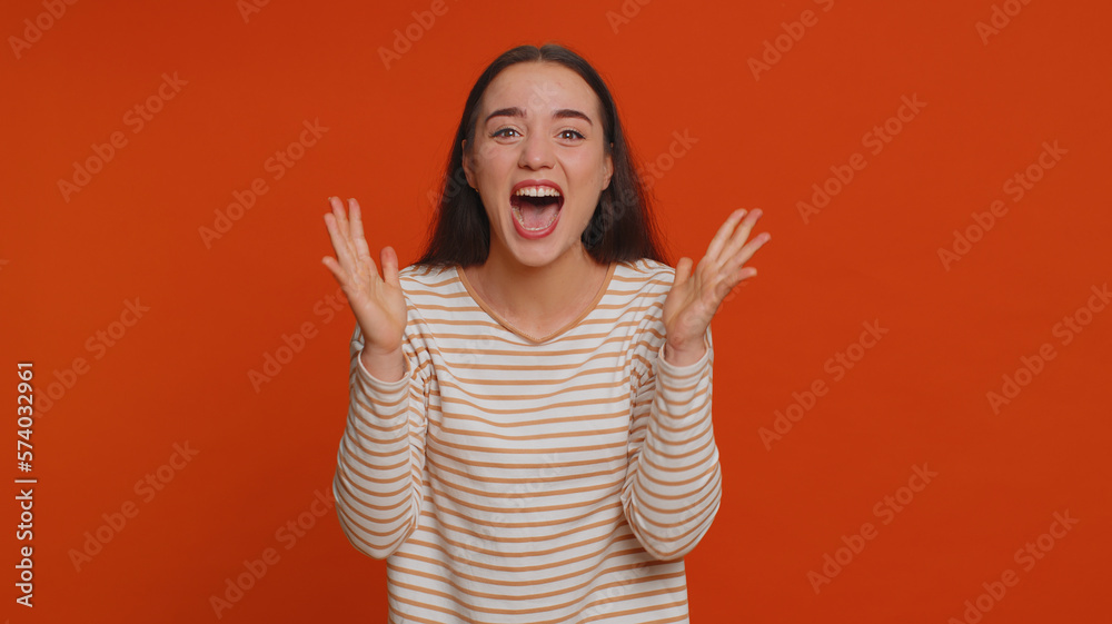 Happy joyful pretty woman in pullover shouting, raising fists in gesture I did it, celebrating success, winning, birthday, lottery jackpot goal achievemen. Adult girl indoors on red studio background Happy joyful pretty woman in pullover shouting, raising fists in gesture I did it, celebrating success, winning, birthday, lottery jackpot goal achievemen. Adult girl indoors on red studio background