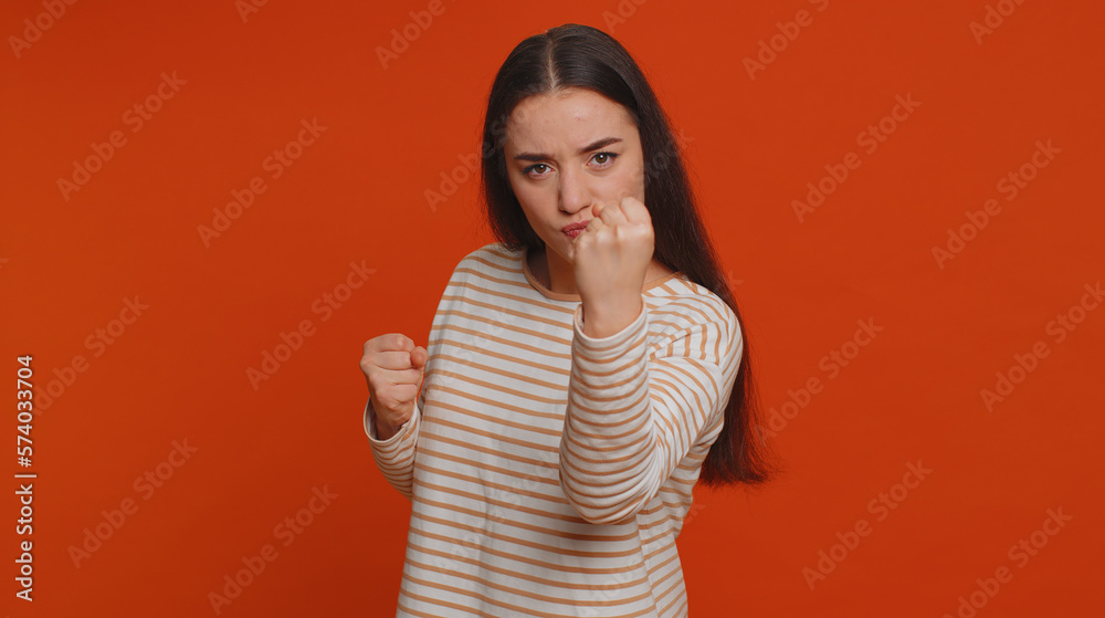 Angry aggressive pretty woman trying to fight at camera, shaking fist, boxing with expression, punishment, disappointment, rage, quarrel. Young adult girl isolated alone on red studio wall background Angry aggressive pretty woman trying to fight at camera, shaking fist, boxing with expression, punishment, disappointment, rage, quarrel. Young adult girl isolated alone on red studio wall background