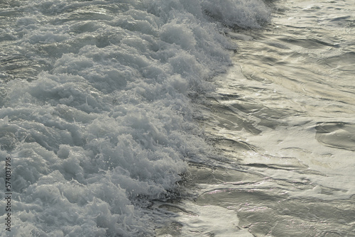 Rough waves sea arriving with white foam at sunset photo