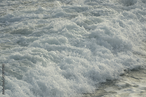 Rough waves sea with white foam at sunset photo