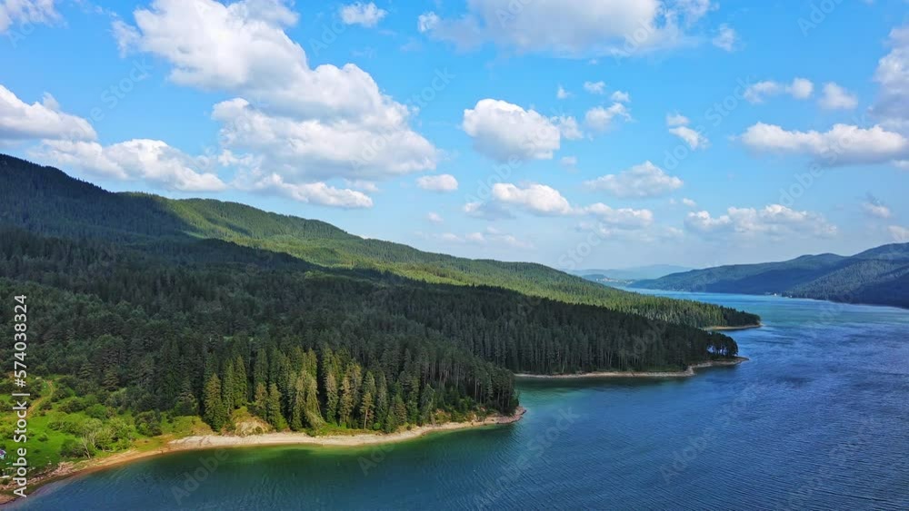 Lake with clear water and stone shore in spruce forest with fir trees against a daytime sky Lake with clear water and stone shore in spruce forest with fir trees against a daytime sky