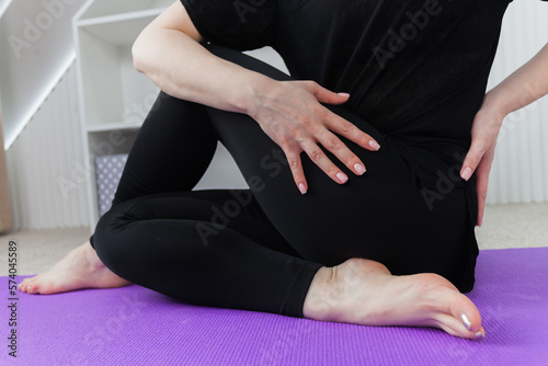 Young woman practicing yoga, working out, wearing sportswear, black top and pants, indoor full length, clear bright background. Sport and healthy active lifestyle concept.